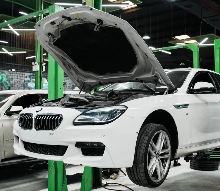 Engine bay inspection under way on a BMW raised on a lift in the Dubai workshop