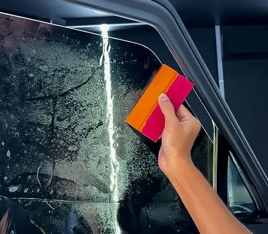 Car window tinting installation on a side window at System X Car Polish in Al Quoz, Dubai