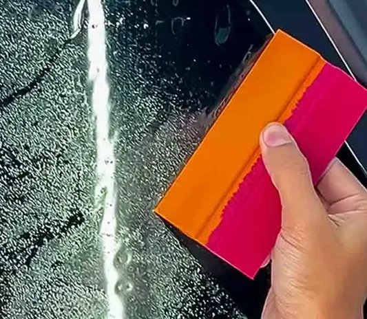 Close-up of a car window tint film being fitted at the System X Car Polish workshop in Dubai
