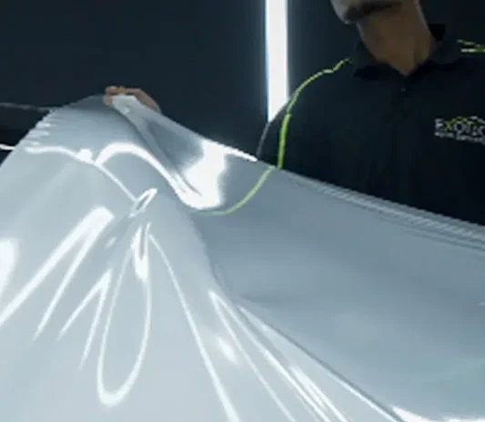 Technician fitting wrap film during a car wrapping installation in Dubai