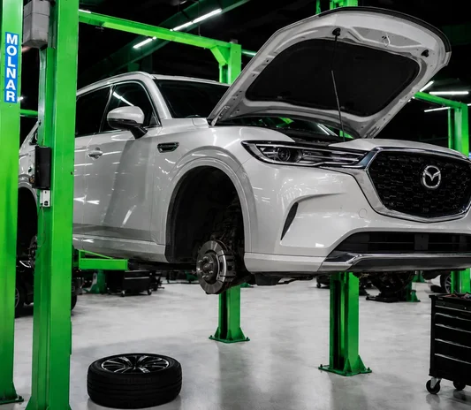 SUV raised on a lift with a wheel removed for inspection at the System X Car Polish workshop in Dubai